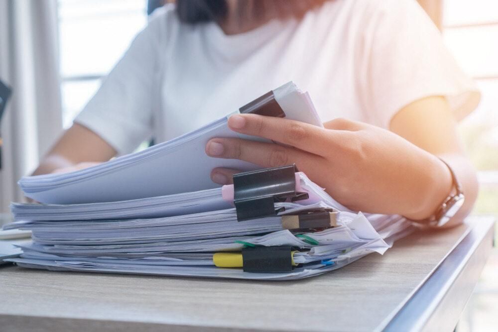 A Woman is Sitting at a Desk Holding a Stack of Papers — Advanced Industry Training In South Townsville, QLD