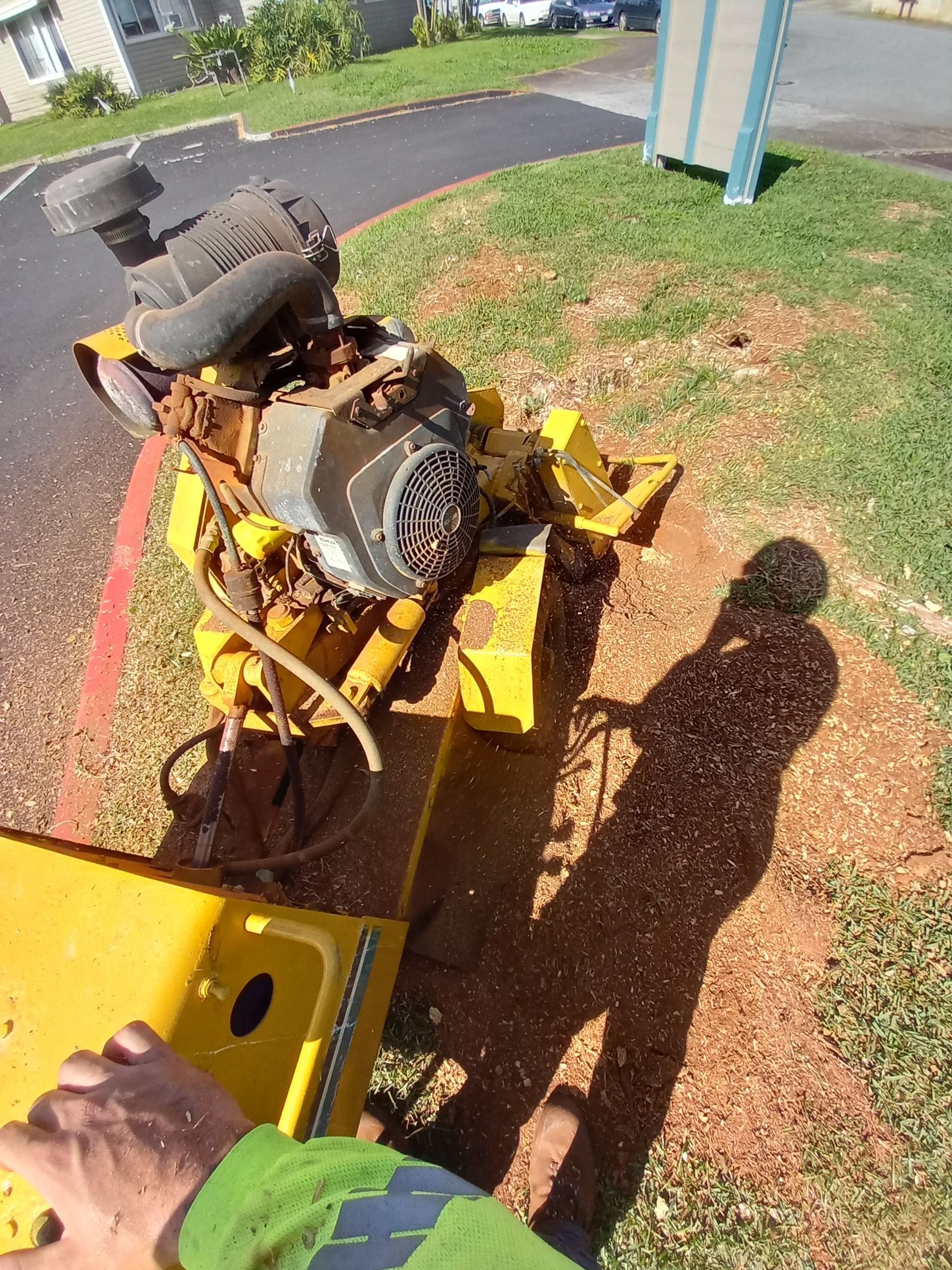A yellow stump grinder grinding a tree stump into wood chips.