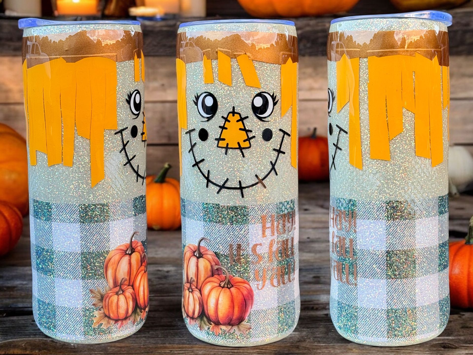Three fall-themed tumblers decorated as scarecrows, with pumpkins and plaid pattern.