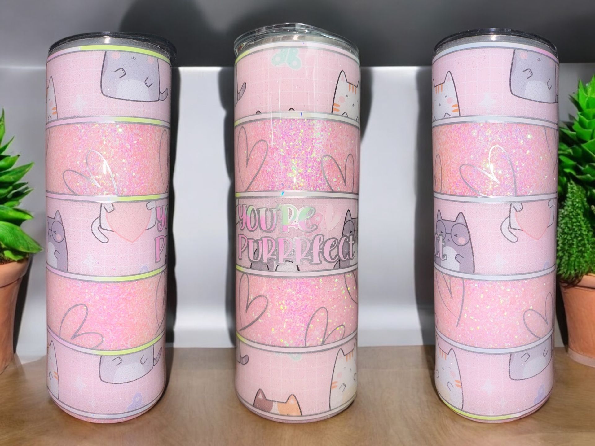 Three pink glitter cat-themed tumblers, with a “YOU DO THE MOON” quote on the middle one.