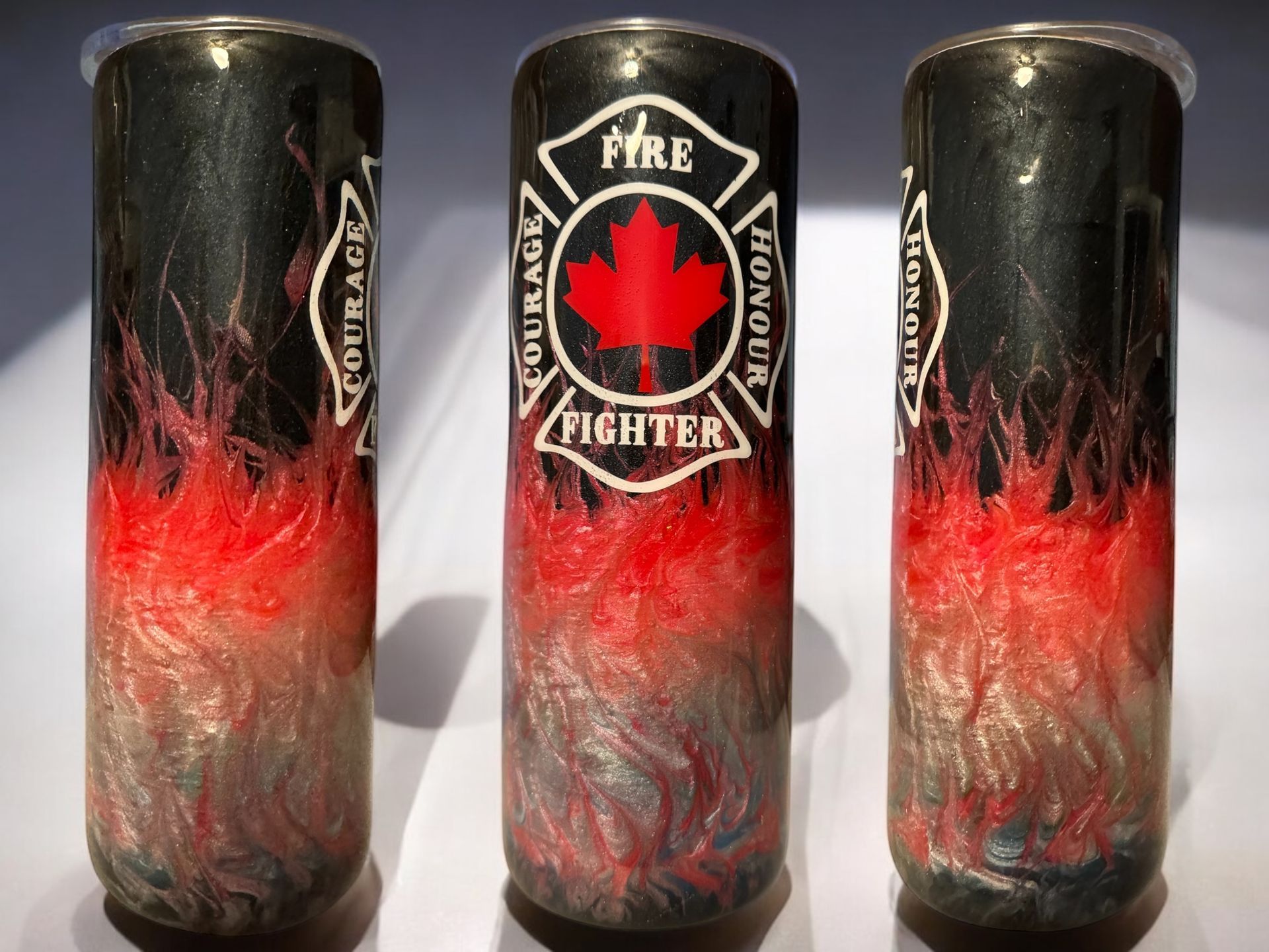 Two customized insulated tumblers. One features a fire fighter logo, the other an abstract blue and green design.
