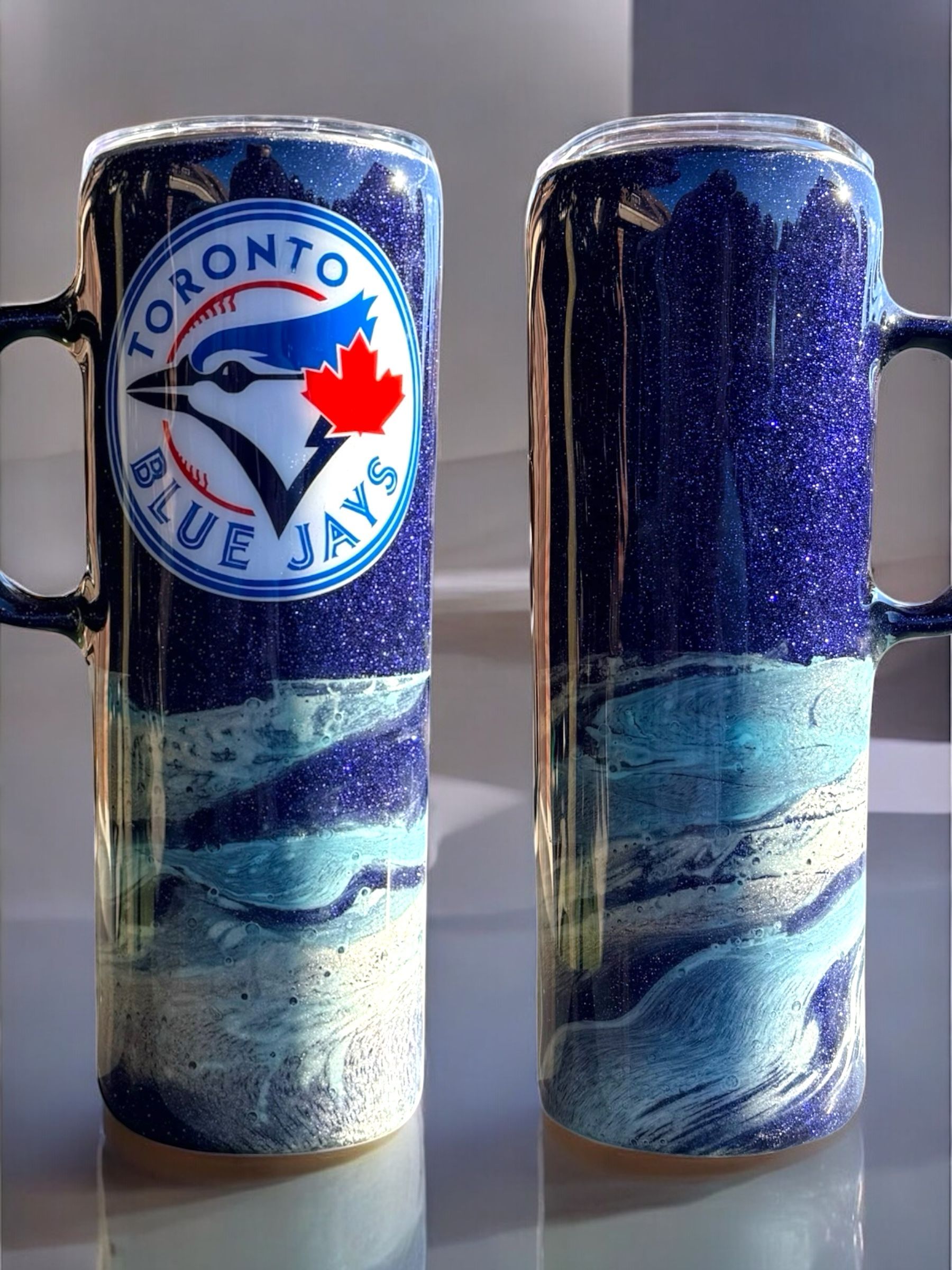 Two glittery mugs with Toronto Blue Jays logo. Blue, white, and silver colors.