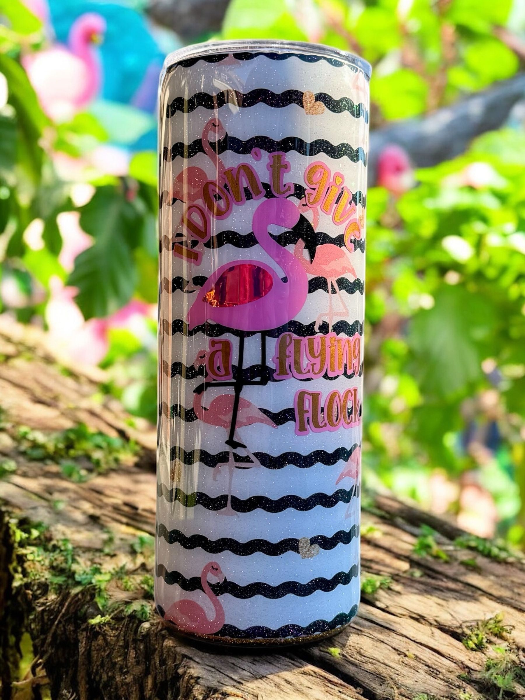 Three glittery flamingo-themed tumblers with floral and striped designs.