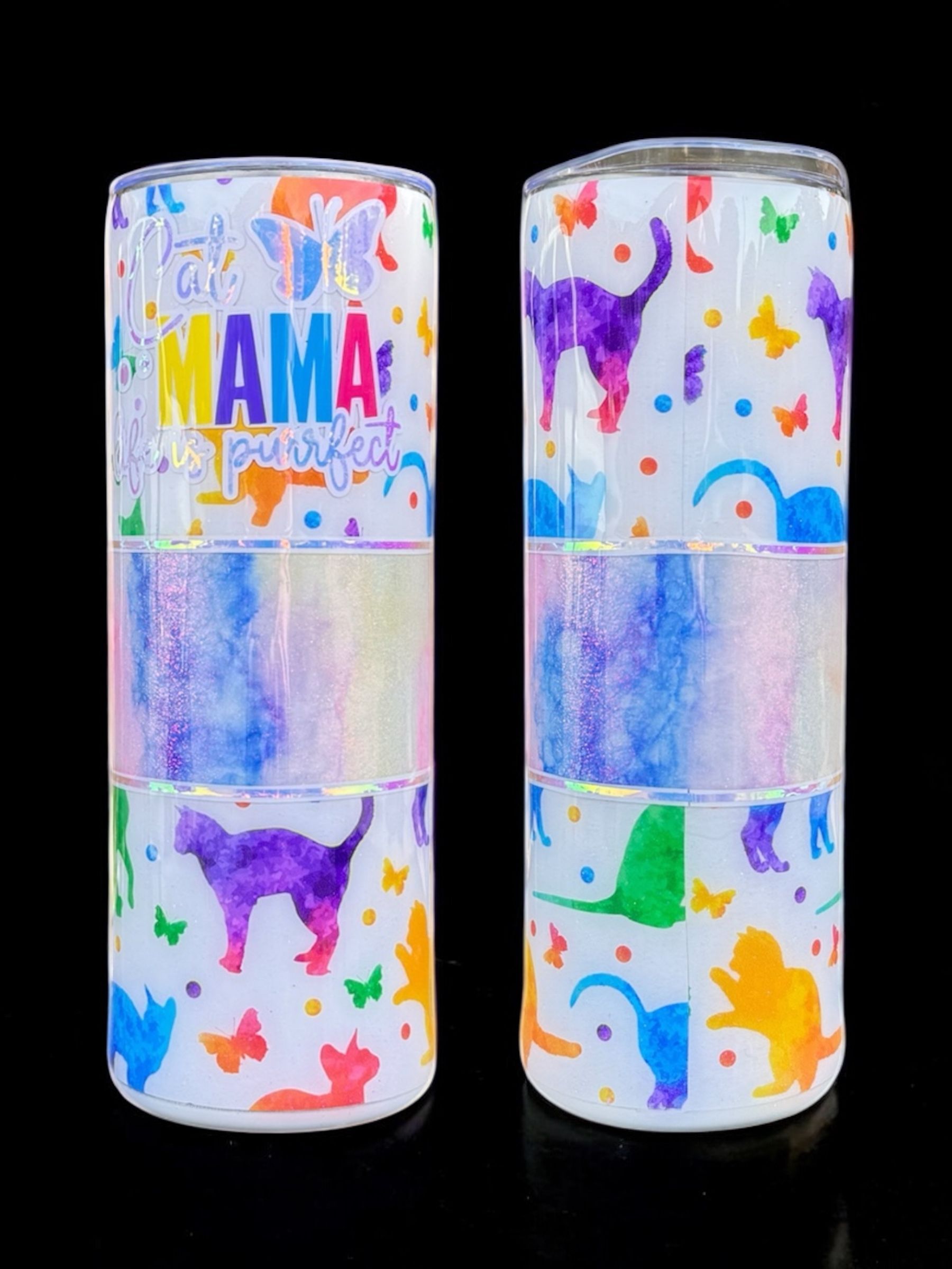 A custom-decorated tumbler with dinosaur and butterfly designs, set on a black surface.