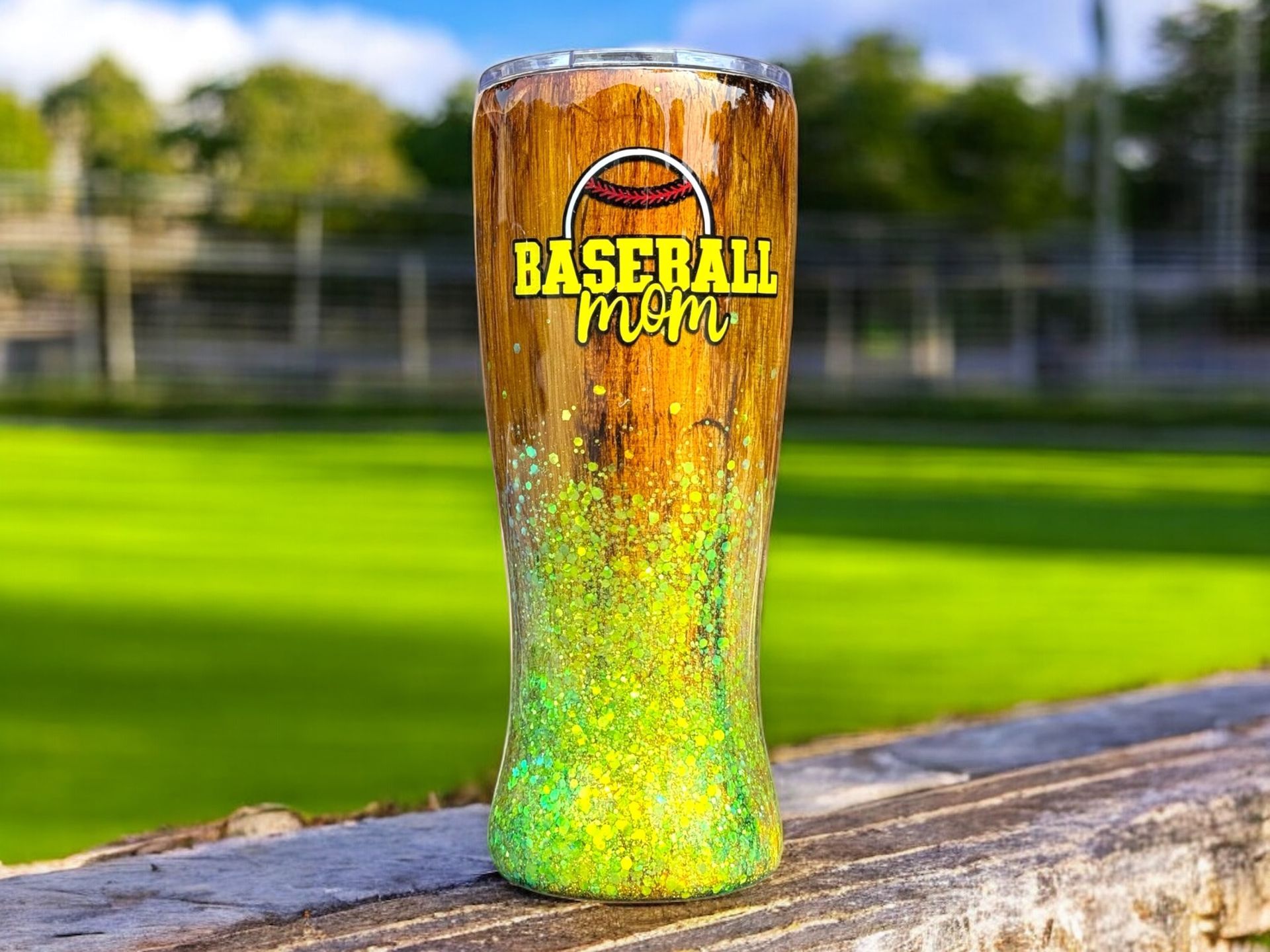 Three wood-grain tumblers with yellow-green glitter bottoms; the middle one reads 