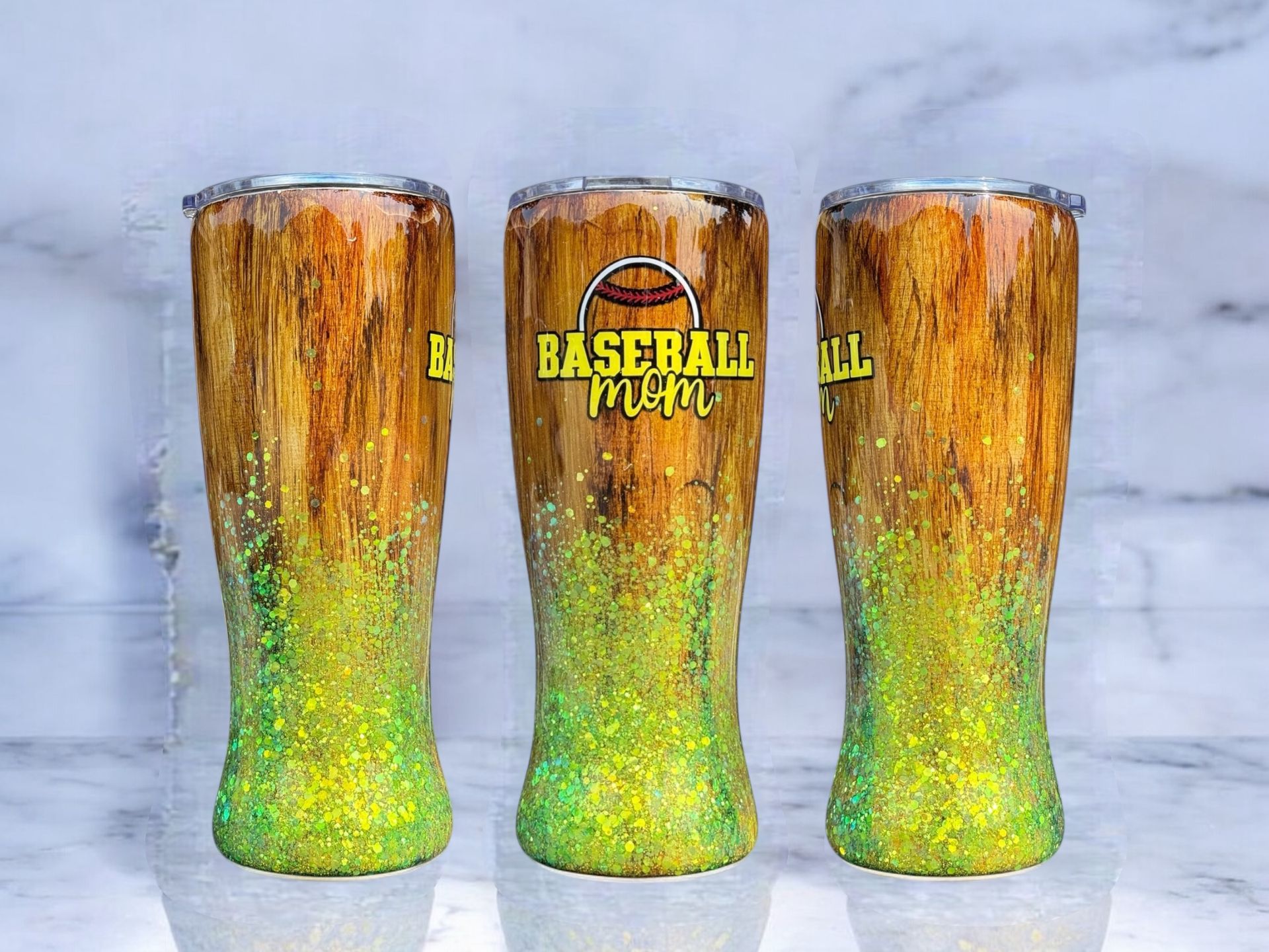 Three wood-grain tumblers with yellow-green glitter bottoms; the middle one reads 