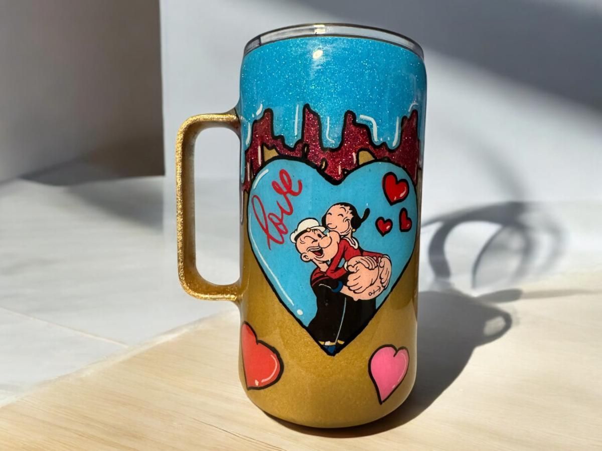 Popeye and Olive Oyl embrace on a heart-decorated, glittery mug. 