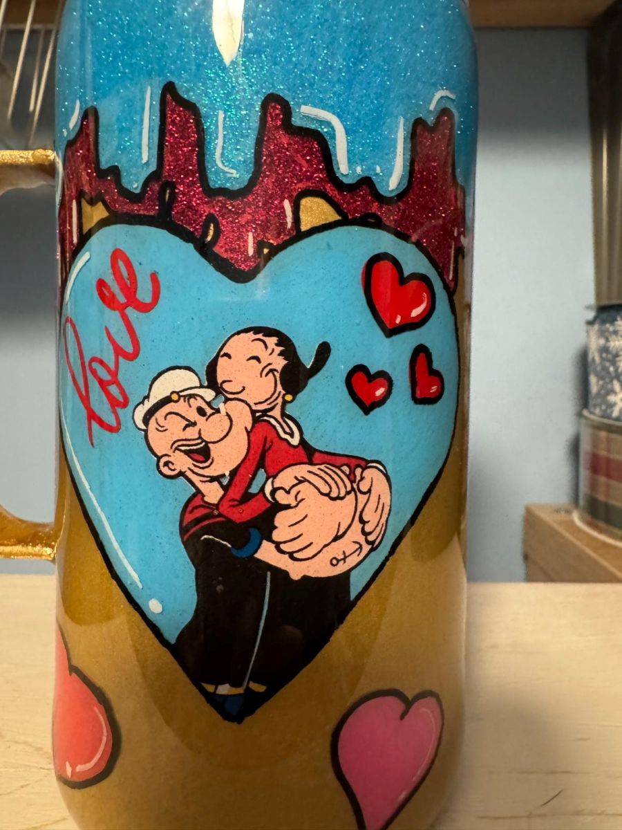 Popeye and Olive Oyl embrace on a heart-decorated, glittery mug. 