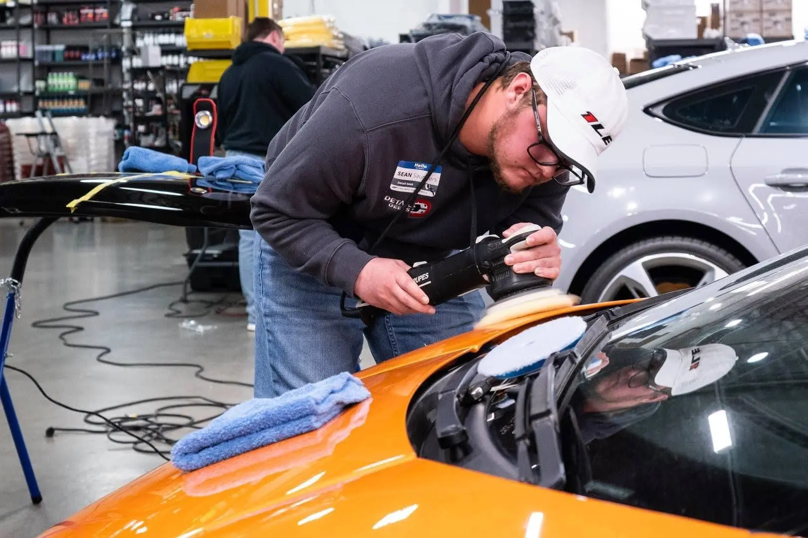 A man is polishing a car in a garage.