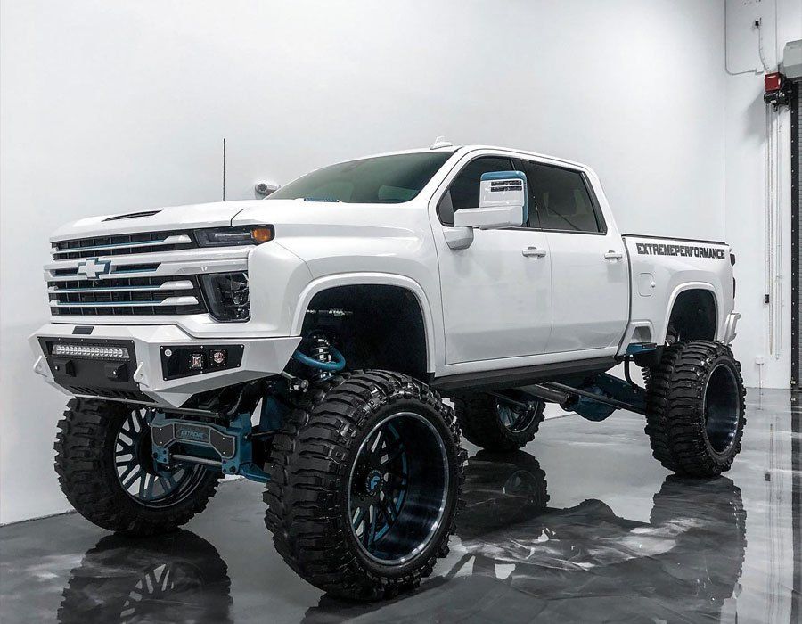 A white truck is parked in a garage with a lot of wheels.