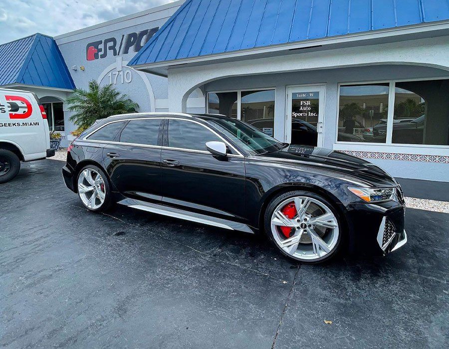 A black car is parked in front of a building.