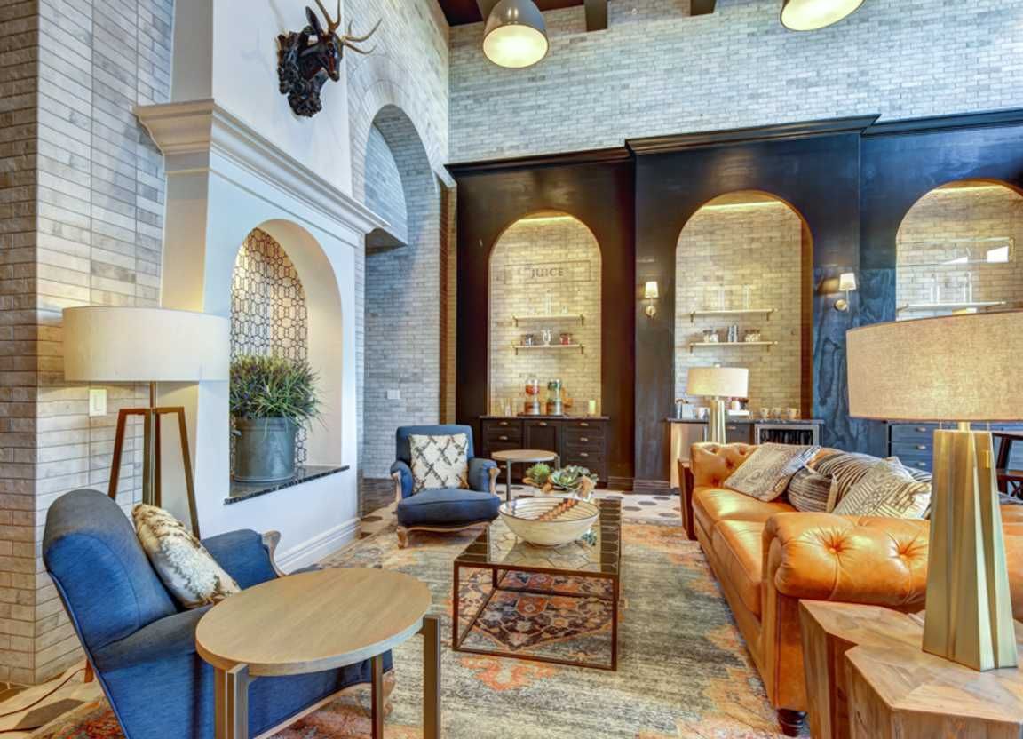Cozy lounge area with a tan leather sofa, blue armchairs, and arched alcoves with decorative shelving.