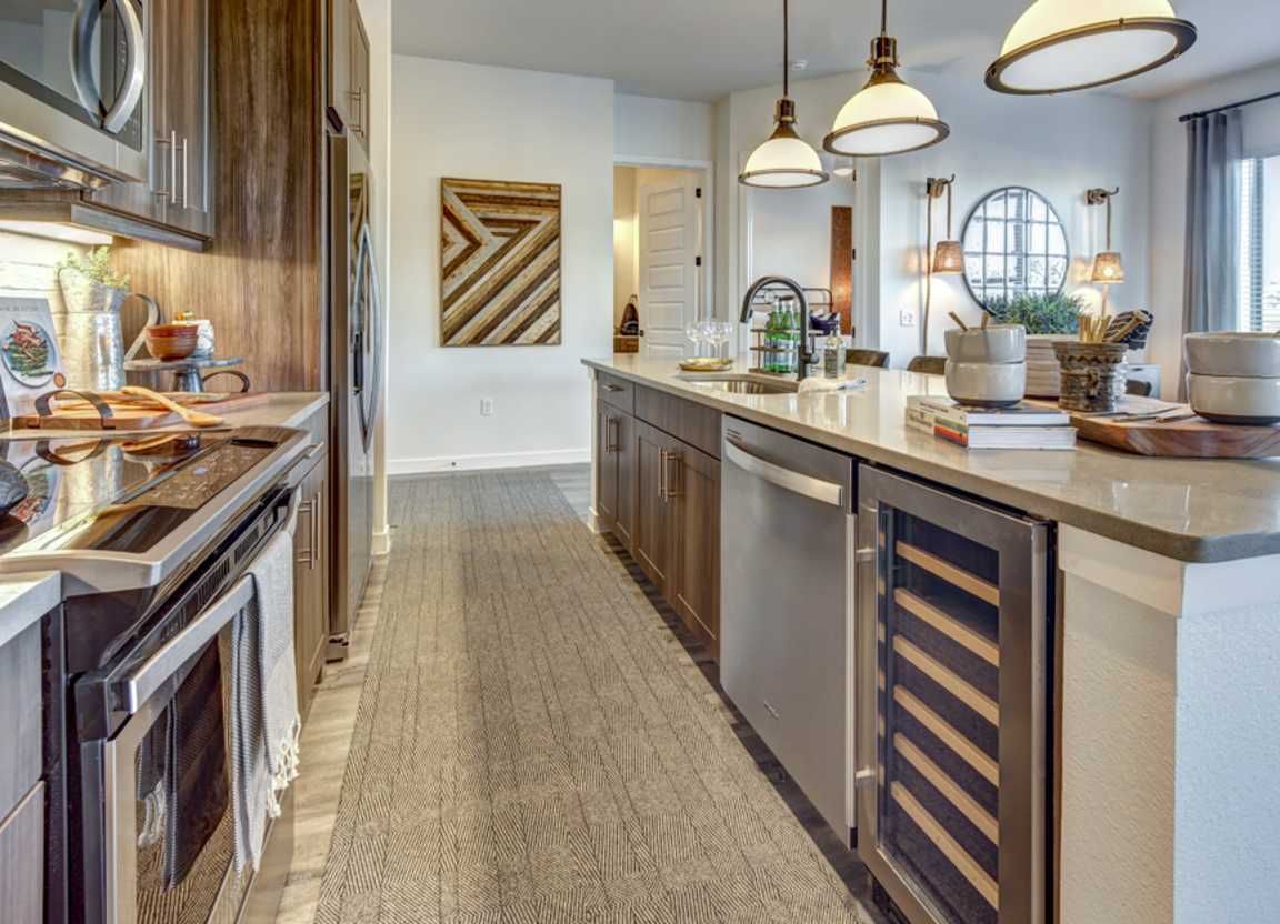 Modern kitchen with wooden cabinetry, stainless steel appliances, and a long island with seating.