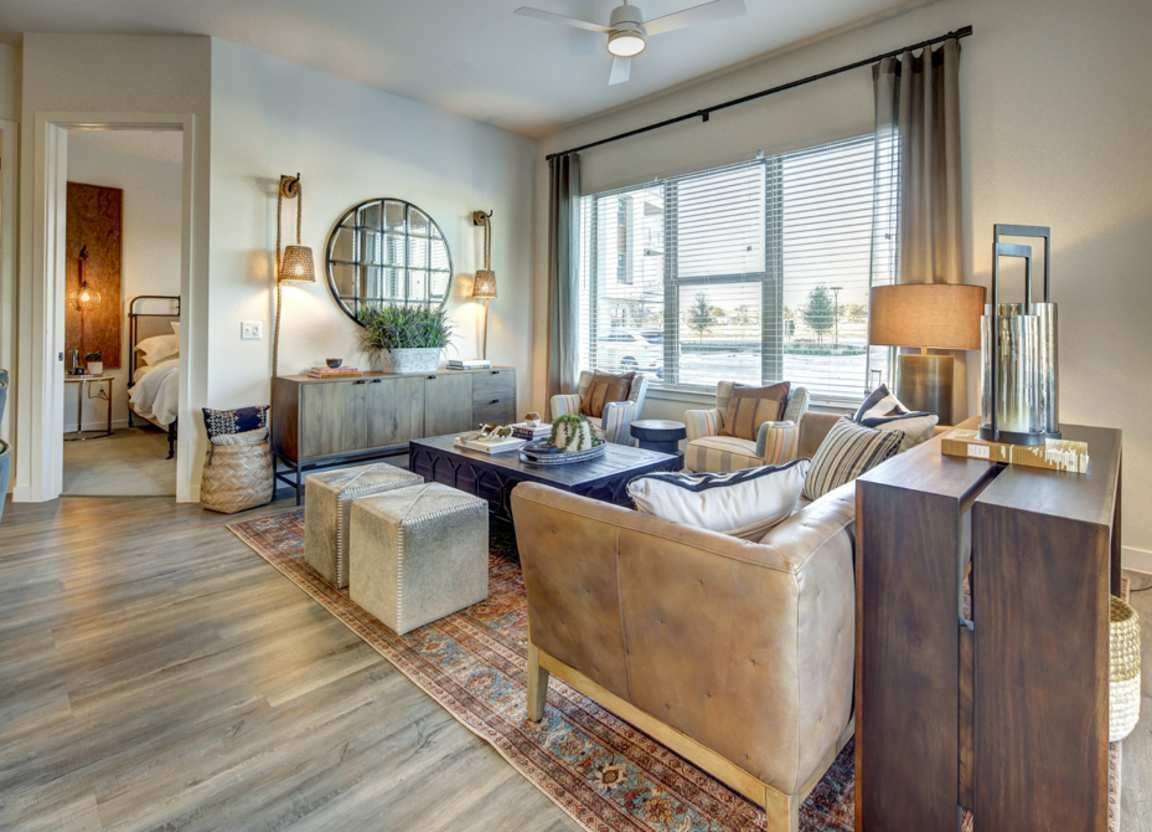 Spacious living room with leather sofa, rug, and large windows overlooking a body of water, open to a bedroom.