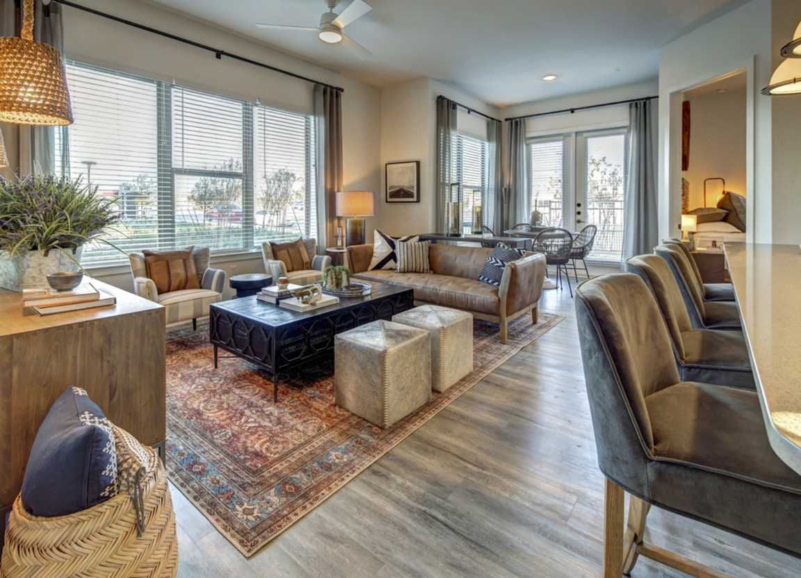 Living room with leather sofa, area rug, and open to dining area with outdoor access.
