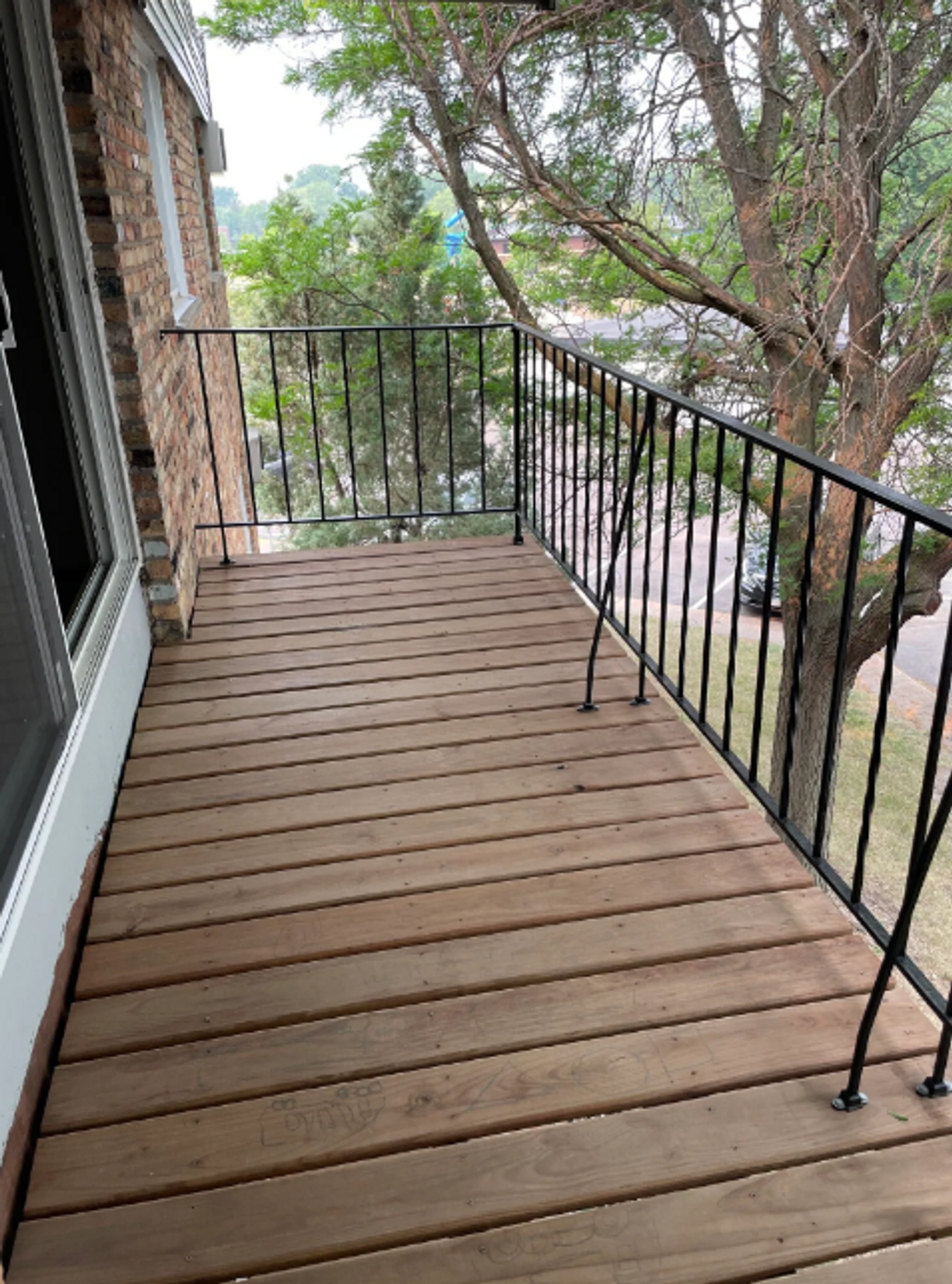 A balcony with a wooden deck and a metal railing.