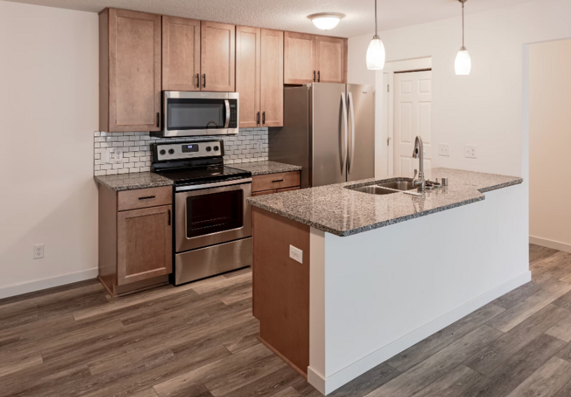A kitchen with stainless steel appliances , granite counter tops , and wooden cabinets.