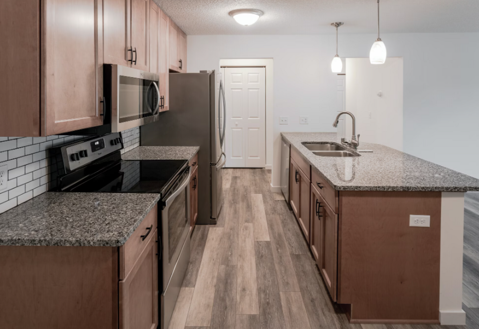 A kitchen with granite counter tops , stainless steel appliances , and wooden cabinets.