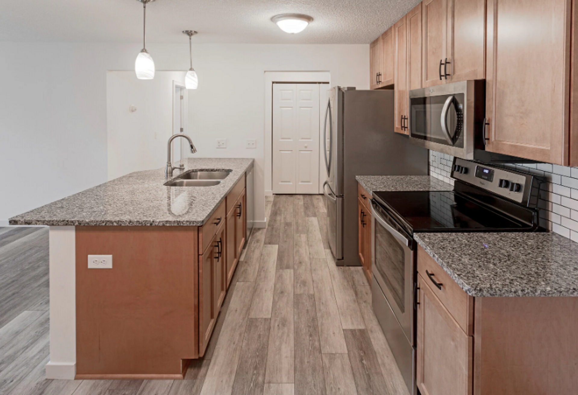 A kitchen with granite counter tops , stainless steel appliances , and wooden cabinets.