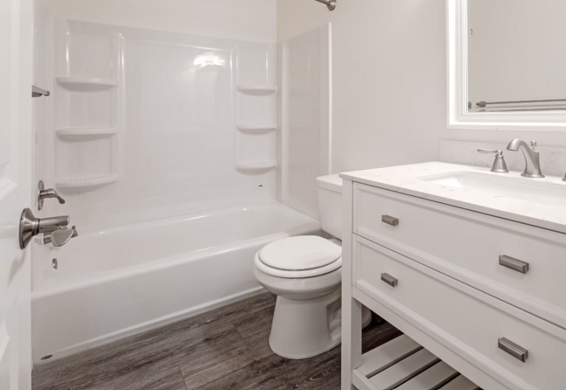 A bathroom with a toilet , sink , bathtub and mirror.