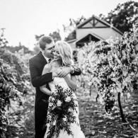 Couple embracing outdoors in a garden, with a building in the background