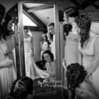 Bridal party in a room, gathered around a bride in a white wedding gown and veil.