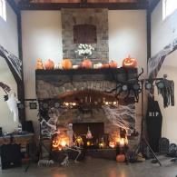 Halloween-decorated stone fireplace with glowing candles, pumpkins, and jack-o'-lanterns in a living room