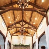 Wood-beamed vaulted ceiling with warm lights and a chandelier in a chapel-like room