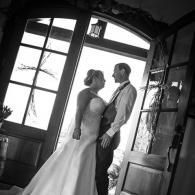 Bride and groom standing close in a doorway, facing each other in black-and-white photo