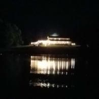 Lit building reflected in calm water at night