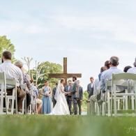Outdoor wedding ceremony with bride and groom standing at the altar before seated guests
