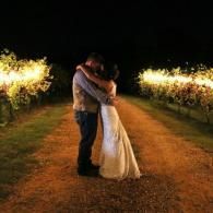 Couple embracing on a lit path at night, surrounded by glowing lights