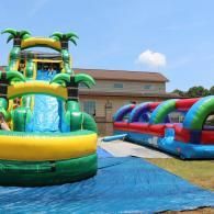 Colorful inflatable water slides on a grassy lawn near a building under a blue sky