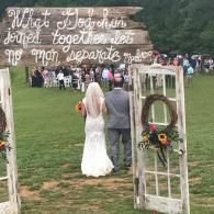 Bride and groom walking through a rustic arch at an outdoor wedding