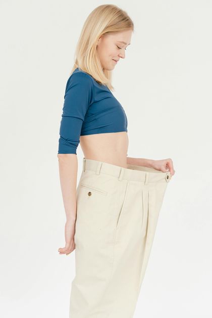 A woman is wearing a blue crop top and khaki pants.