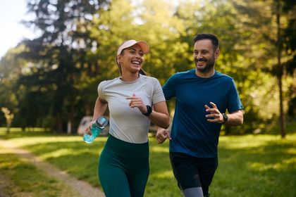 A man and a woman are running in a park.