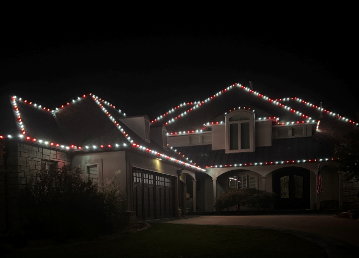A house with christmas lights on the roof at night