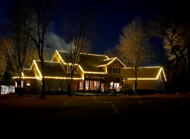 A large house is lit up with christmas lights at night.