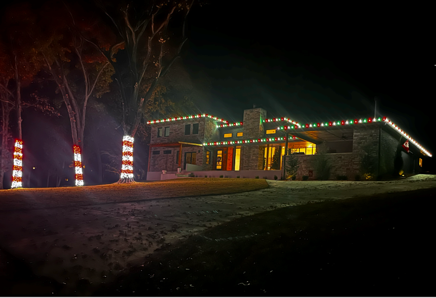 A large house is decorated with christmas lights at night.