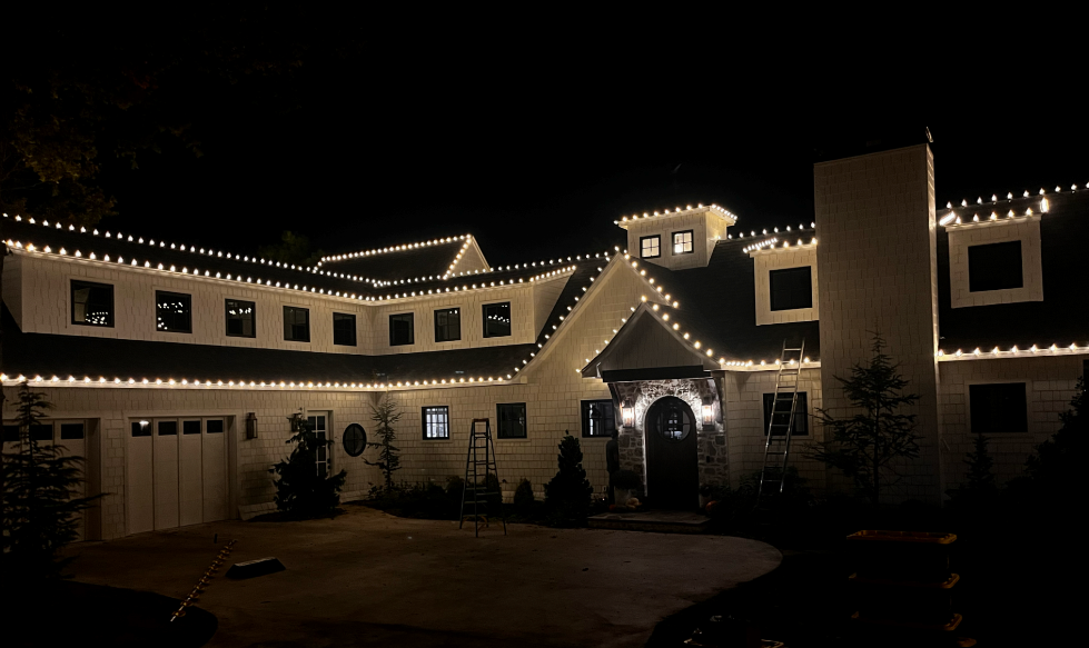 A large white house is lit up with christmas lights at night.