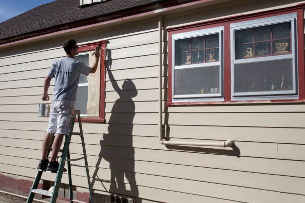 A man working on the exterior of a house, representing a residential painting company at work.