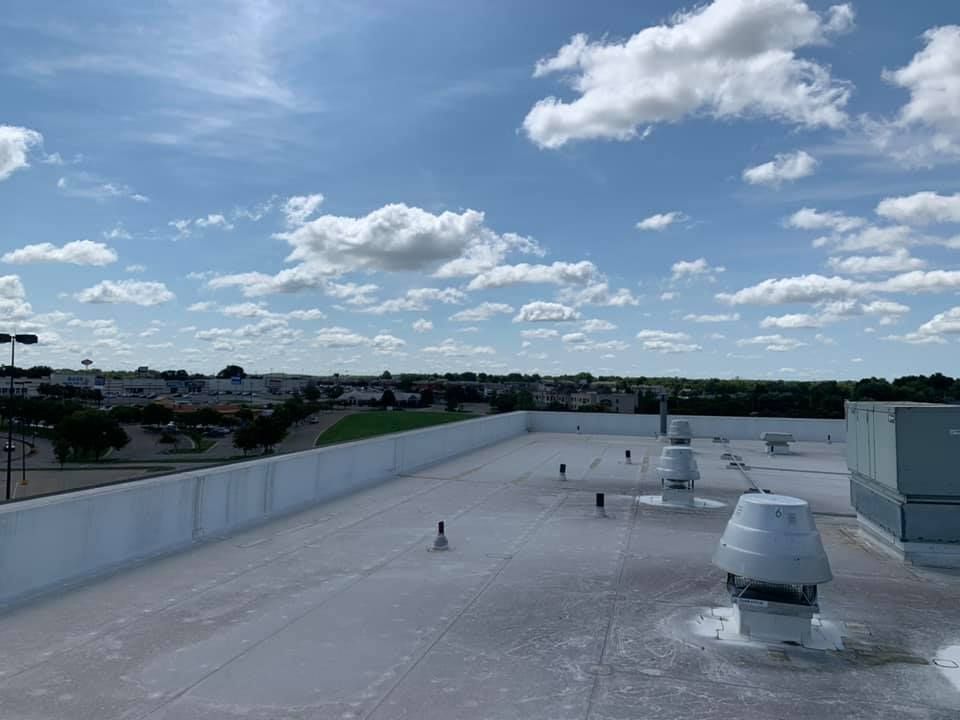 The roof of a building with a blue sky and white clouds in the background.