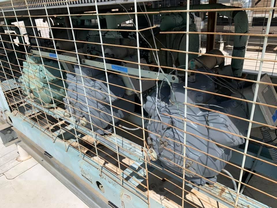 A large machine is behind a fence in a factory.