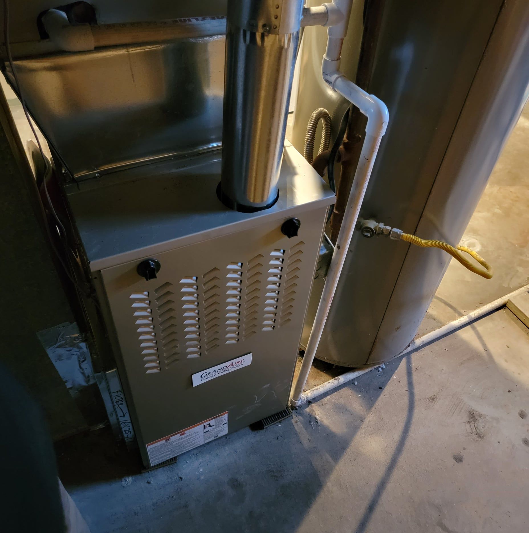 A gas heater is sitting next to a water heater in a room.