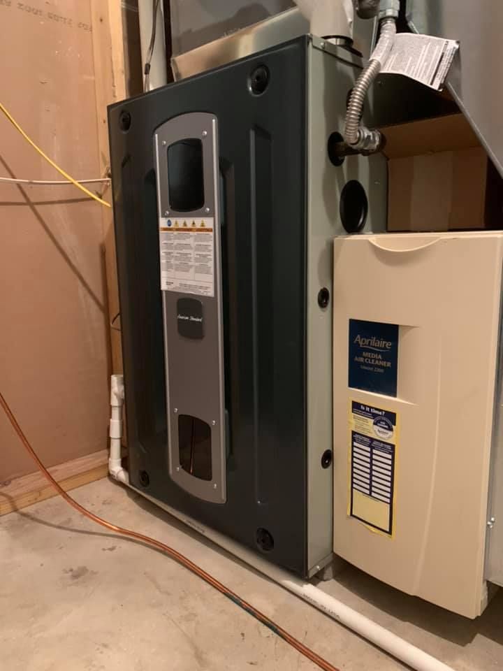 A black and white heater is sitting in a basement next to a white box.
