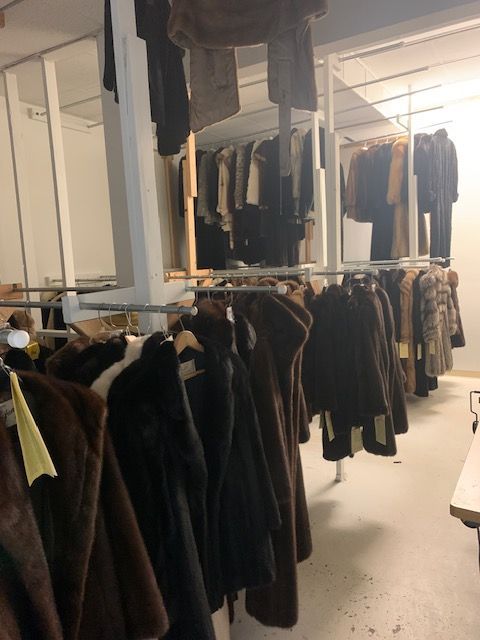 A row of fur coats hanging on racks in a store