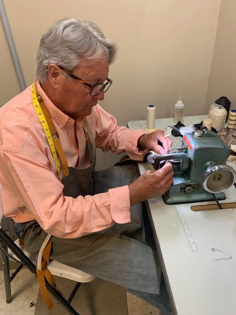 A man in a pink shirt is working on a sewing machine