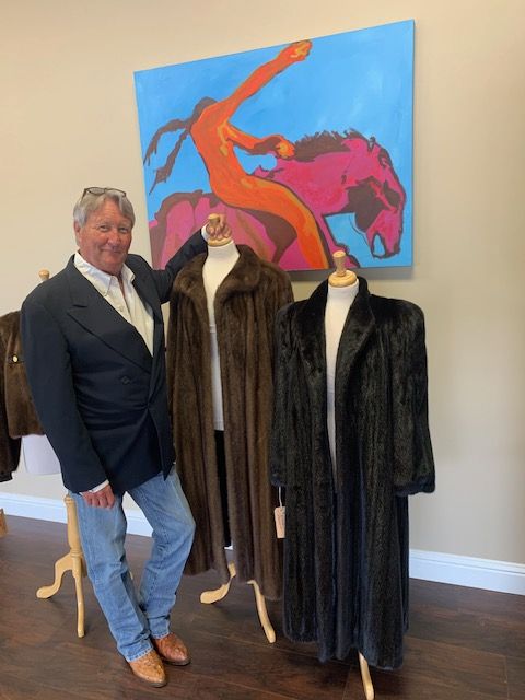 A man stands in front of a painting of a woman riding a horse