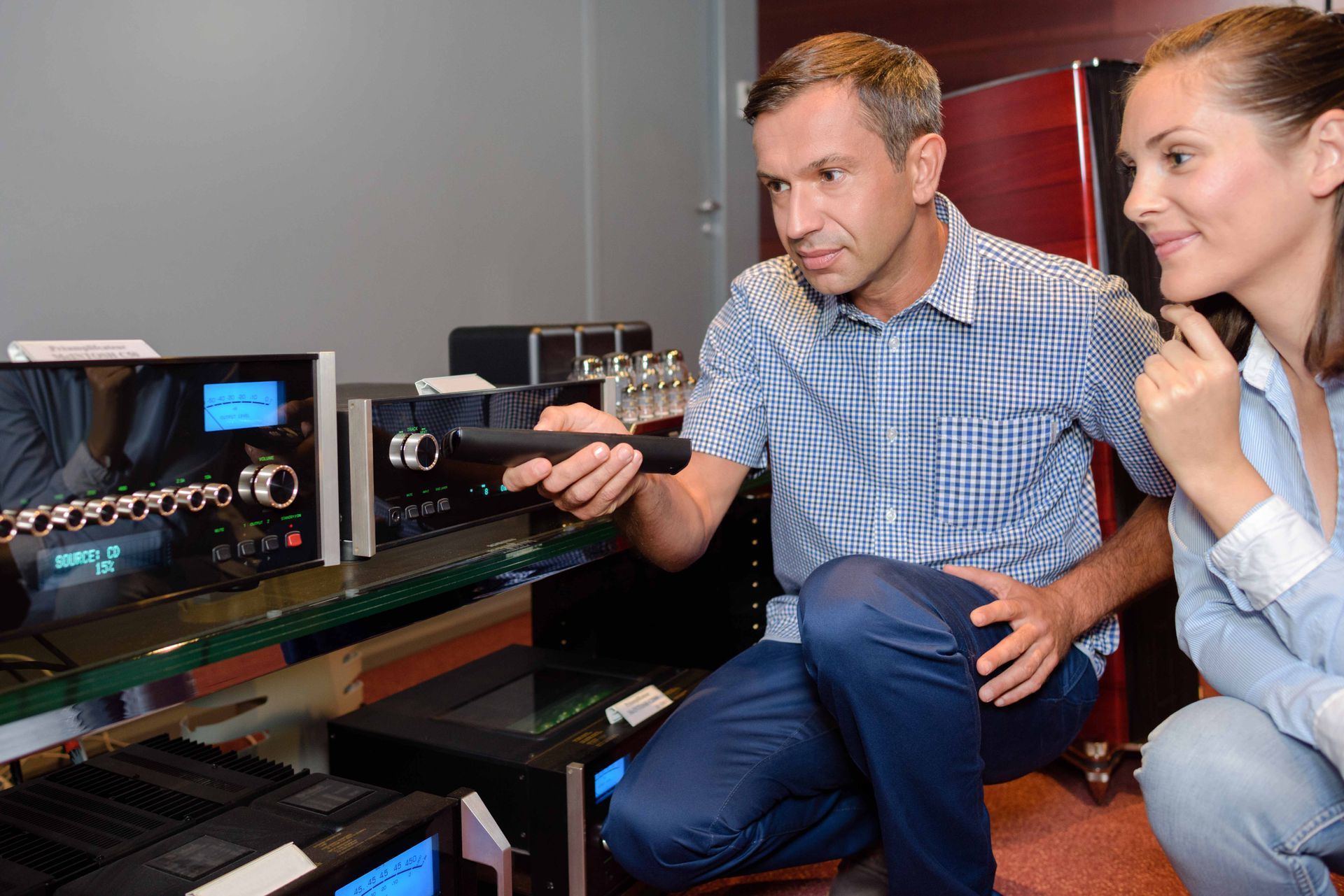 a man and a woman are looking at a stereo system in a store