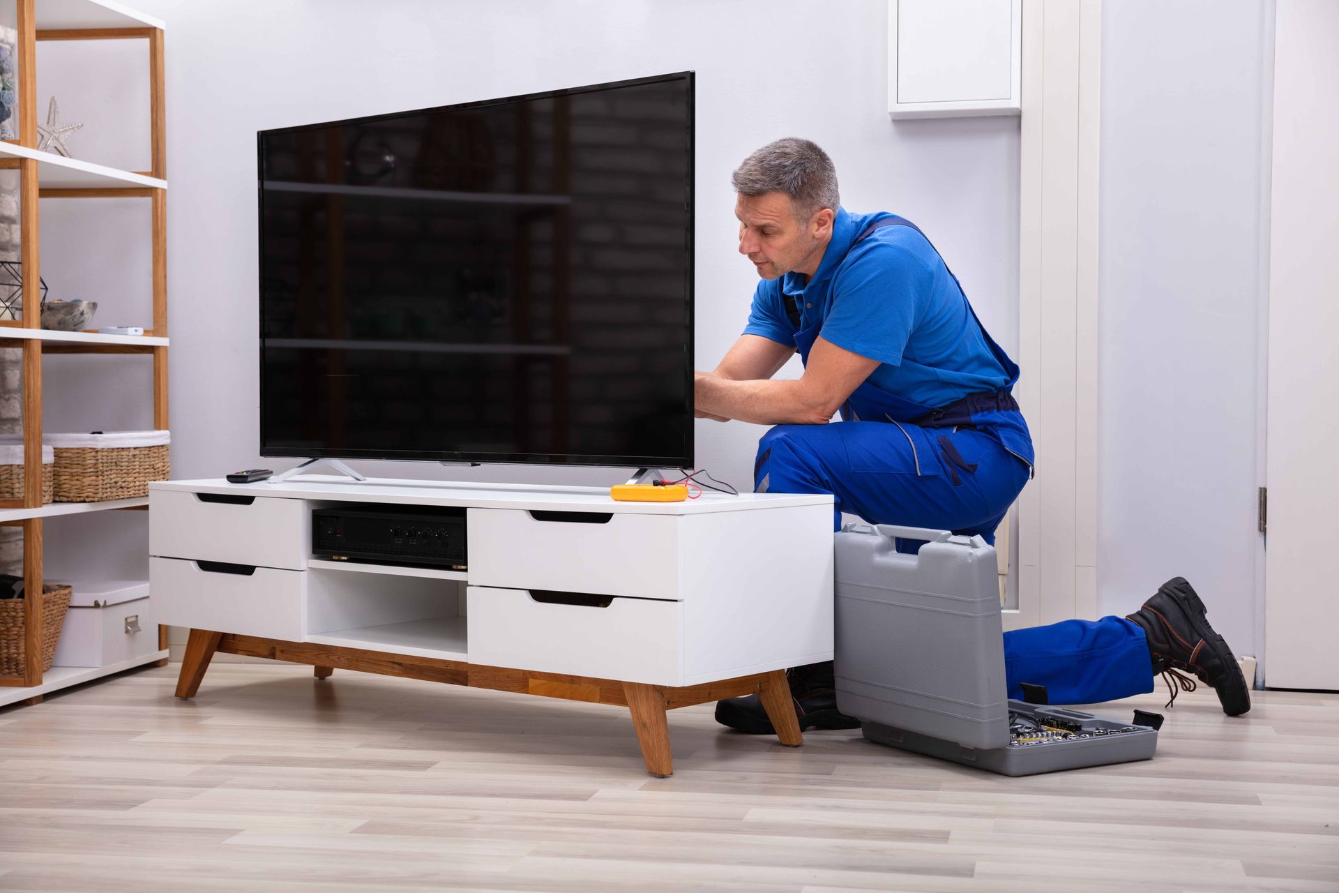 a man is fixing a flat screen tv on a stand in a living room